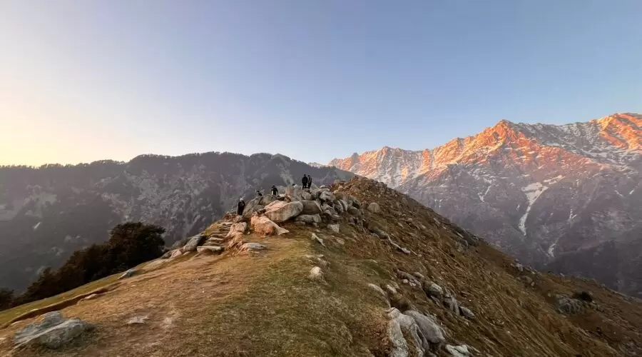 Scenic view of the Dhauladhar mountains with a trekking trail leading to Triund, promoting Hill Hikers' guided triund trek booking services.